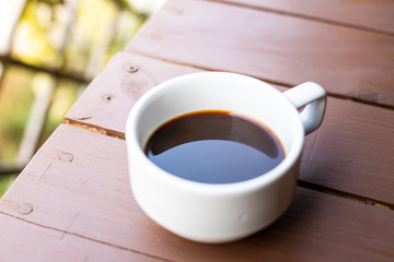 Closeup of white coffee  cup with hot coffee on wood Table.