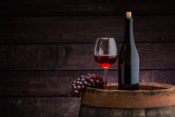 Fototapeta na wymiar red wine bottle and wine glass on wodden barrel