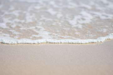 beautiful soft wave on sand at the sea sunny day. subject is blurred.