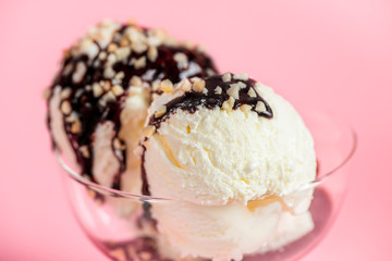 scoops white ice cream decorated chocolate topping and nuts on vase over pink background