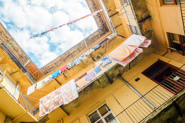 Linen is Dried on Clothesline on a Background of Blue Sky with Clouds. Sunny day in the Yard-Well. Old Building Facade