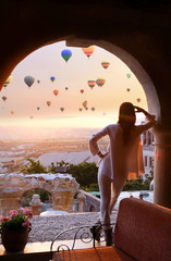 Girl at dawn watching the balloons and enjoying life. Cappadocia, Goreme, Turkey  - obrazy, fototapety, plakaty