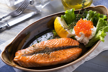 Tasty grilled salmon fillet with cream and caviar on a plate. Closeup