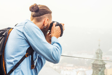 Obraz premium Traveler Young Man with a Beard Photographs Attractions and Panorama of the Ancient City from a High Observation Platform. Travel Tourism Concept