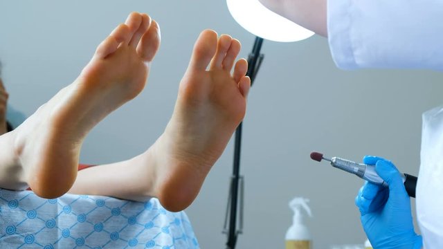 Callus peeling using professional pedicure drill machine. Spa foot treatment. Removing hard, callused skin for soft feet.