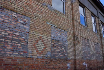 big brown wall of an old brick house with windows on the street