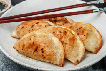 Fried dumplings with meat (beef, pork) or seafood, cabbage and spices in a white plate close-up. ...