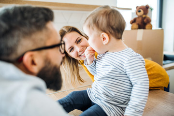 A portrait of young family with a toddler girl moving in new home.