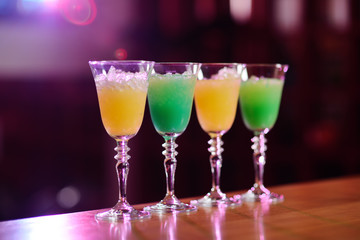 four cocktails of yellow and green flowers on the bar close-up