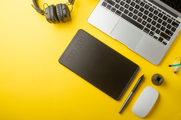 Top view of the workplace designer. Creative designer, graphics tablet, laptop, and accessories for the graphic designer.Flat lay.On yellow background