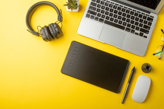 Desktop designer, and creative retoucher with a graphics tablet, laptop, glasses. Design, flat lay. On a yellow background - Powered by Adobe