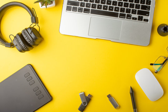 Top view of the workplace designer. Creative designer, graphics tablet, laptop, and accessories for the graphic designer.Flat lay.On yellow background