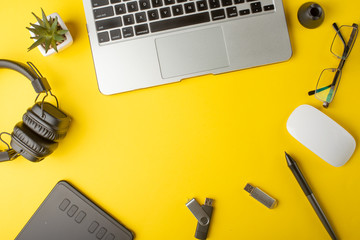 Desktop designer, and creative retoucher with a graphics tablet, laptop, glasses. Design, flat lay. On a yellow background