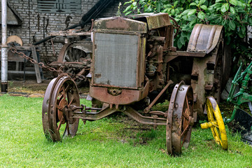 Old rusted and destroyed tractor abandoned outside on a rainy day