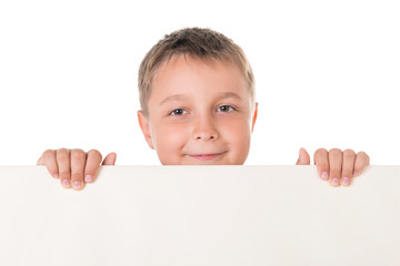 Smiling handsome boy male teenager posing behind white panel on white background. Advertising space for billboard poster