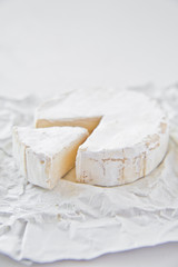Brie cheese on white paper. White background, side view, close-up