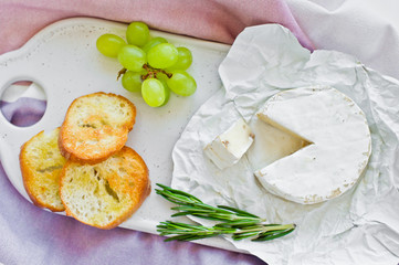 Camembert cheese with nuts on a white cutting Board, grapes, rosemary. White background, top view
