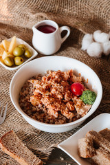 Russian traditional dish, healthy food, proper nutrition. Boiled Buckwheat with minced pork, tomato, broccoli in a white plate and sliced ​​bread next to a wooden background.
