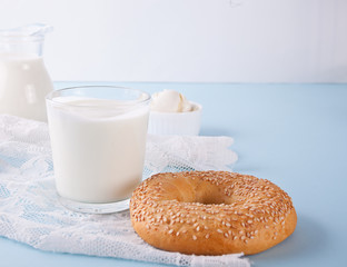 Yogurt in glass and fresh bagel on a table with white napkin.