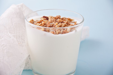 Granola with yogurt in glass with wooden spoon on a table.