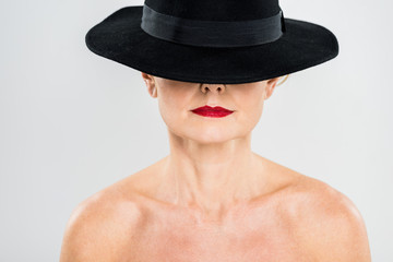 middle aged elegant and fashionable woman with red lips in black hat isolated on grey