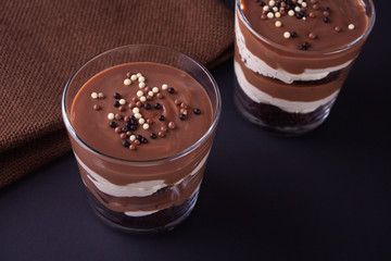 Chocolate dessert in glass jars on a table with wooden spoon
