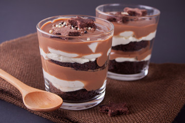 Chocolate dessert in glass jars on a table with wooden spoon