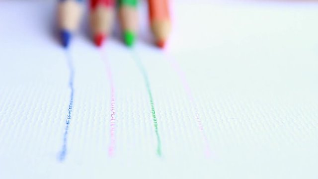 Artists hands drawing 4 colors pencil, blue red green orange writes line on white paper background together.