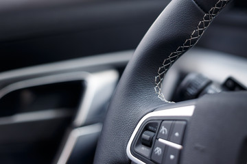 Obraz premium Multimedia leather steering wheel in a modern expensive car. Perforated leather steering wheel. Modern car interior details. Car detailing. Selective focus