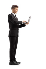 Young guy in a suit standind and using a laptop