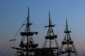 cruise vacation medieval vintage ship mast dark silhouette shape on twilight blue evening sky...