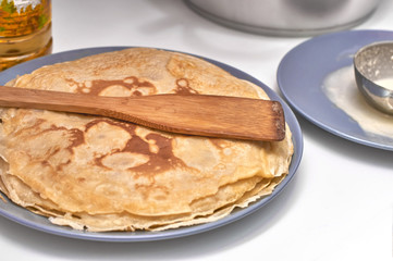 Pancakes on a gray plate and wooden paddle, white background