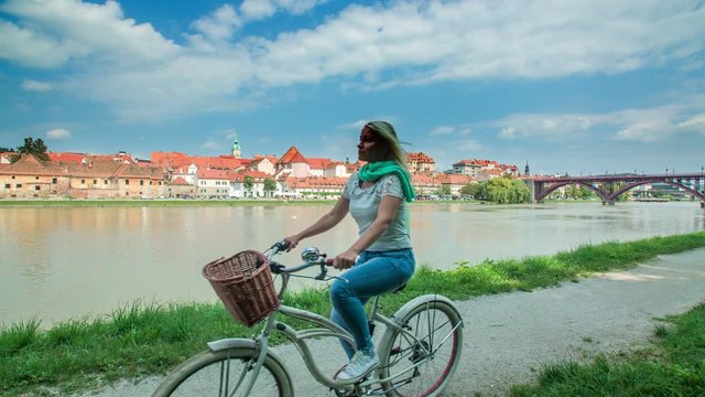 This young woman is going for a ride with her bicycle on a gorgeous sunny day. The day is warm and we can see a nice city of Maribor.