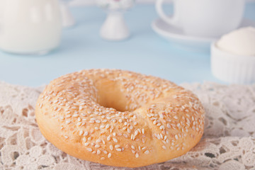 Fresh healthy bagel on a white napkin with cup of coffee, cream cheese and eggs for breakfast.