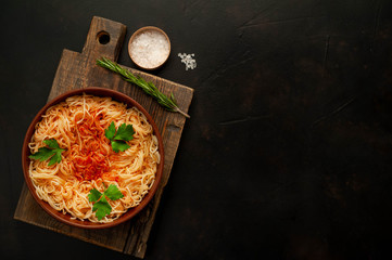 Appetizing Italian pasta spaghetti with tomato sauce, Parmesan cheese on a plate against a background of stone. Top view, with copy space.