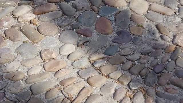 Pan close-up view of cobblestone street made of stones of various sizes in slow motion