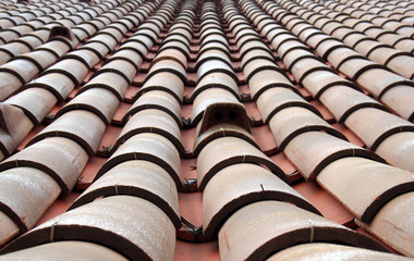 a full frame close up perspective view of traditional red clay pantiles on a roof with focus near the foreground in rows