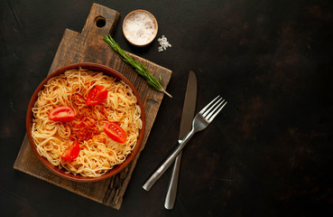 Appetizing Italian pasta spaghetti with tomato sauce, Parmesan cheese on a plate against a background of stone. Top view, with copy space.