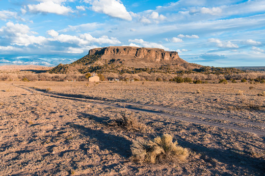 Old adobe church set in the desert landscape below Black Mesa and the Sangre de Cristo Mountains near Santa Fe, New Mexico