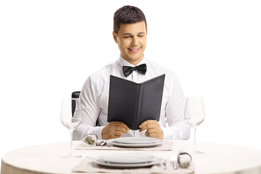 Young Handsome Man At A Restaurant Table Reading A Menu