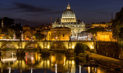 Fototapeta na wymiar Rome at Night - A panoramic night view of Tiber river at Sant' Angelo Bridge, with St. Peter's Basilica towering in background, as seen from the Ponte Umberto bridge. Rome, Italy.