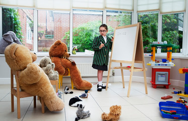 Young girl pretending to be a teacher to her teddy bears