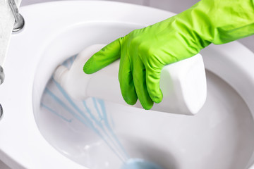 Gloved hand cleaning toilet bowl