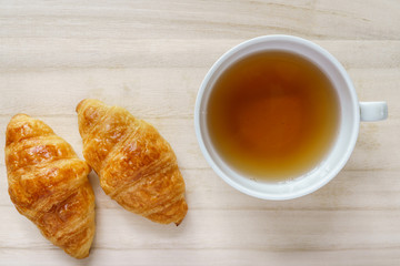 Croissant and a cup of tea on a wooden tray