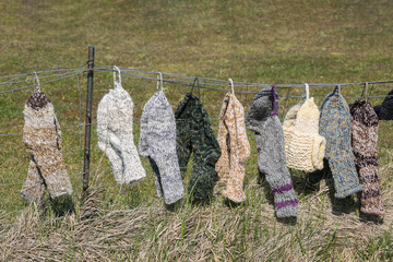 Verschiedene selbstgestrickte Wollsocken hängen auf einer Leine