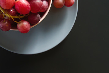 Red grapes on blue plate on black table