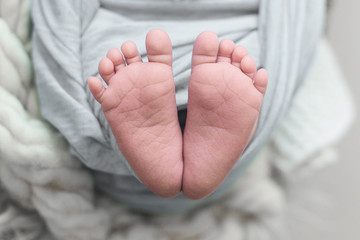 Feet of a newborn baby, toes in the hands of mom and dad, hands and nails of a child, the first days of life after birth, scaly skin