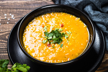 Red lentil soup in black bowl.