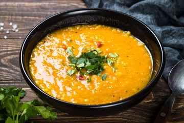 Red lentil soup in black bowl.