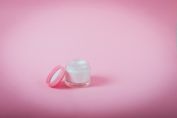 Opened Jar with face or body cream on pink background isolated. Beauty, make up, skincare concept. Selective focus, copy space.